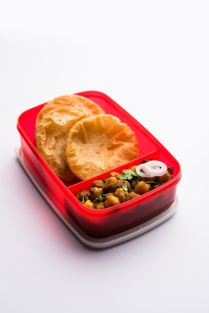 Punjabi Chole lub Choley masala z puri lub poori w pudełku na lunch lub tiffin, selektywne skupienie