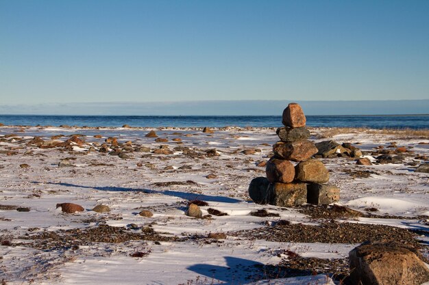 Punkt orientacyjny Inuksuk lub Inukshuk na pokrytej śniegiem arktycznej tundrze w Nunavut w jasny, słoneczny dzień