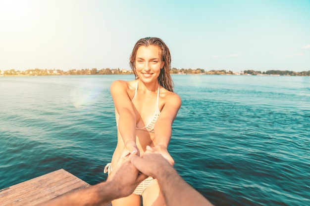 Punkt widzenia młodej kobiety w stroju kąpielowym bawiącej się ze swoim partnerem nad morzem