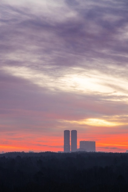 Purpurowe chmury na świcie nad parkiem i wieżami