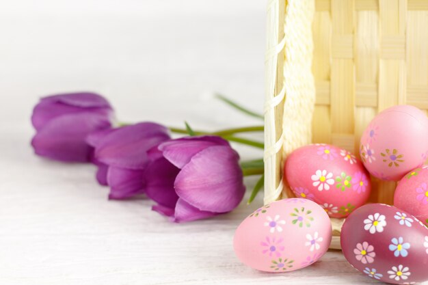 Purpurowi tulipany i Easter jajka na białym drewnianym stole.