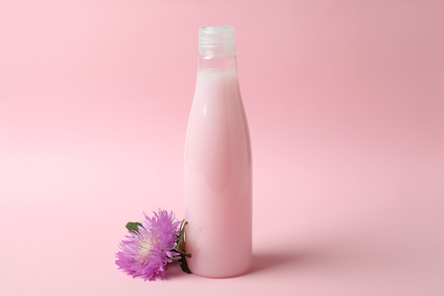 Pusta butelka szamponu i kwiat na różowo