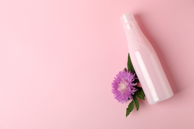 Pusta butelka szamponu i kwiat na różowo