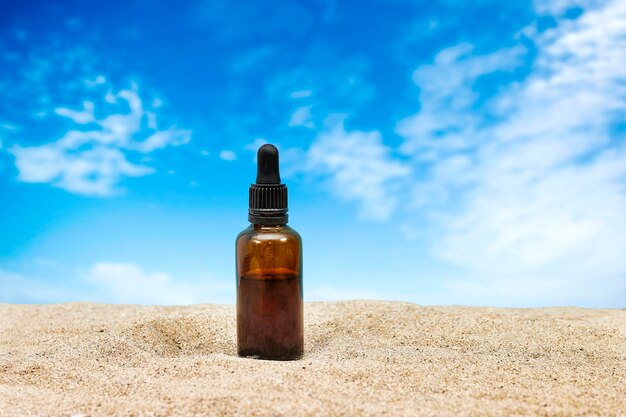 Zdjęcie pusta butelka z eterycznym olejem ze szkła bursztynowego z pipetą na piasku koncepcja pielęgnacji skóry z naturalnymi kosmetykami