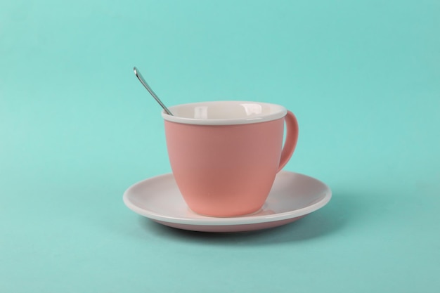 Pusta ceramiczna filiżanka z łyżką na niebieskim tle