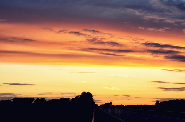 Pusta droga asfaltowa i wschodzące słońce na panoramę.