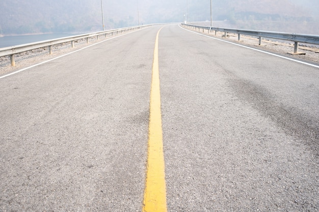 Pusta droga asfaltowa w mglistych warunkach żółta środkowa linia w dzień złej pogody Pasmo górskie.
