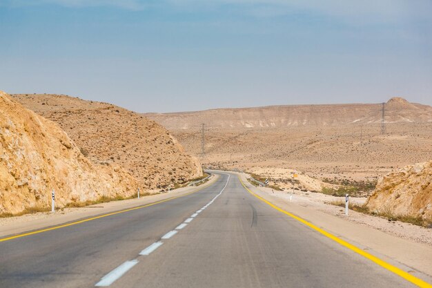 Pusta droga gdzieś wśród skał i piasków na pustyni Negew w pobliżu Mitzpe Ramon w Izraelu