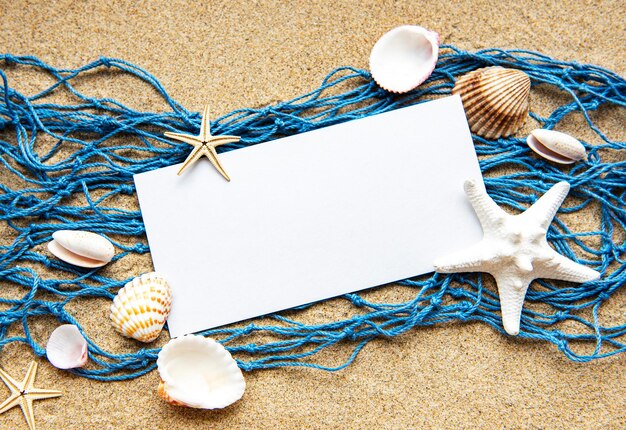 Zdjęcie pusta kartka papieru na piasku na plaży z muszliami morskimi