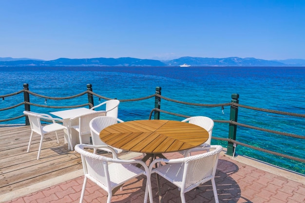 Pusta kawiarnia z krzesłami i stołami nad brzegiem morza pod błękitnym niebem w lecie