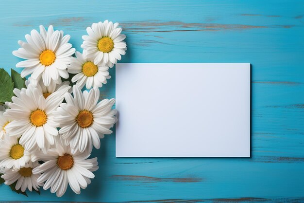 Zdjęcie pusta maketa karty na niebieskim drewnianym tle otoczona margaritami kwiaty szablon biały arkusz papieru do projektowania