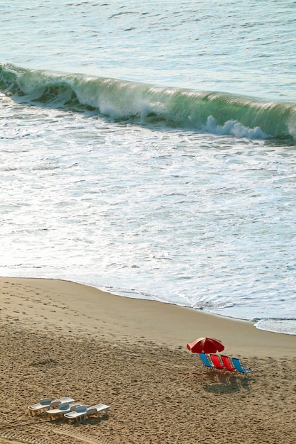 Pusta plaża z krzesłami i parasolem oraz rozbijające się fale na morzu?