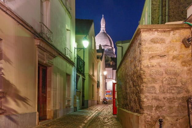 Pusta przytulna ulica i bazylika Sacre-Coeur nocą, dzielnica Montmartre w Paryżu, Francja