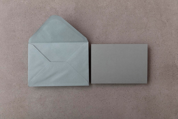Pusta szara karta z szarym papierowym szablonem koperty makiety na betonowym tle
