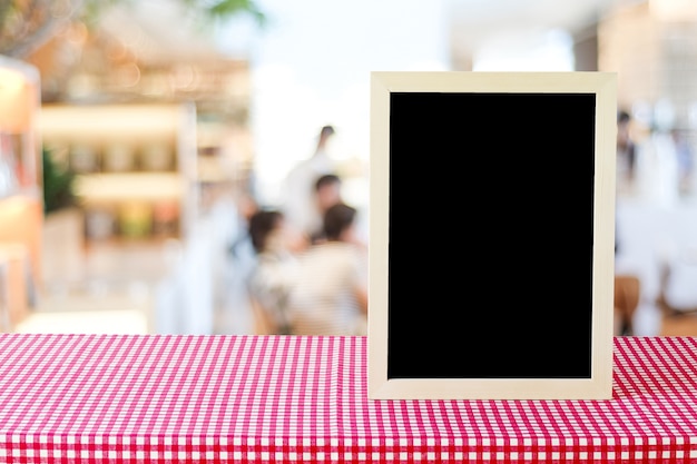 Pusta tablica stojący na czerwony i biały obrus na rozmycie restauracja