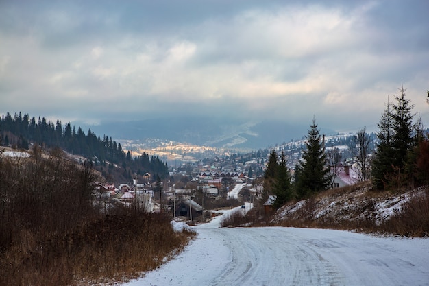 Pusta zimowa droga prowadząca do wioski wśród gór zimowy krajobraz