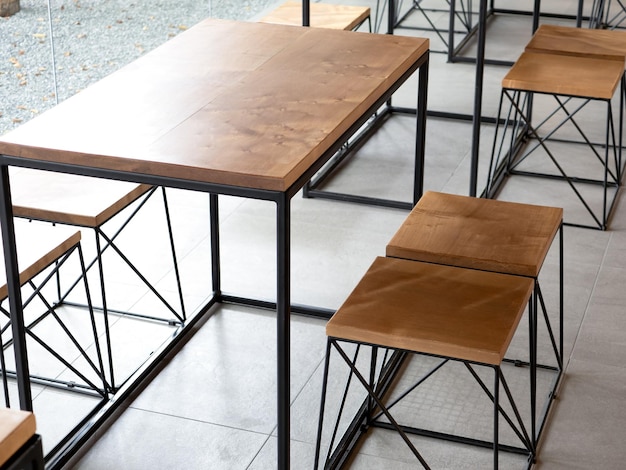 Puste drewno drewnianego stołu z krzesłami na tle płytek cementowych bez ludzi w kawiarni w stylu loftu Puste drewniane meble z dekoracją z czarnego stalowego pręta na betonowym parterze w kawiarni