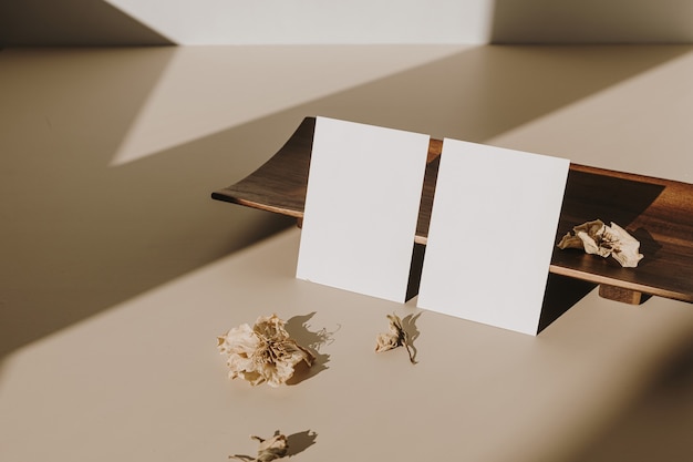Zdjęcie puste kartki papieru i drewniana taca, suche kwiaty z cieniami słonecznymi na beżu