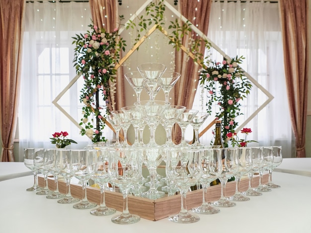 Puste kieliszki do wina na stole to piramida. Piękna ceremonia ślubna w pomieszczeniu.