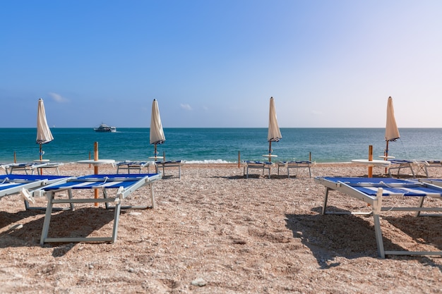 Puste leżaki czekają na wczasowiczów na pięknej plaży.