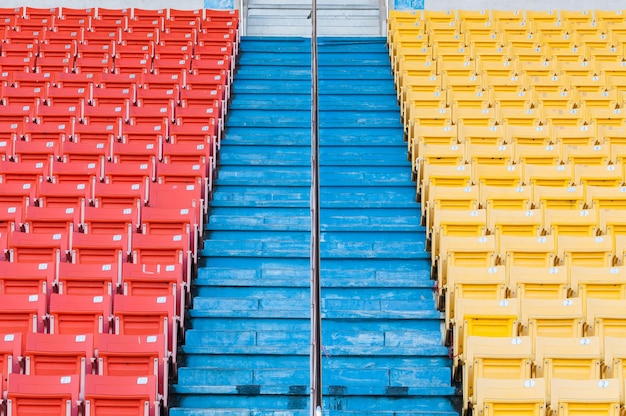 Puste pomarańczowe i żółte siedzenia na stadionieRzędy siedzeń na stadionie piłkarskim