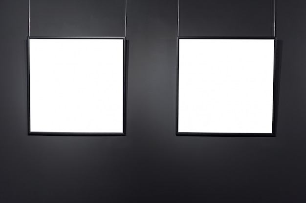 Zdjęcie puste ramki kwadratowe na czarny mur z cegły. puste plakaty lub ramka artystyczna czekają na wypełnienie. kwadratowa czarna ramka tła