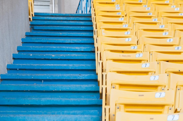 Puste żółte siedzenia na stadionie, Przejście rzędów siedzeń na stadionie piłkarskim