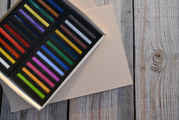 Pusty arkusz papieru kraft lub tektury i kolorowe kredki pastelowe, ołówki, widok z góry, miejsce na kopię