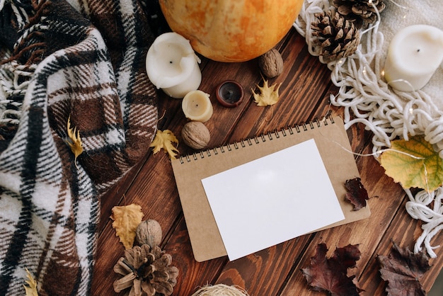 Zdjęcie pusty arkusz papieru na drewnianym stole z góry. jesienny nastrój z liśćmi, świecami, kratą. widok z góry