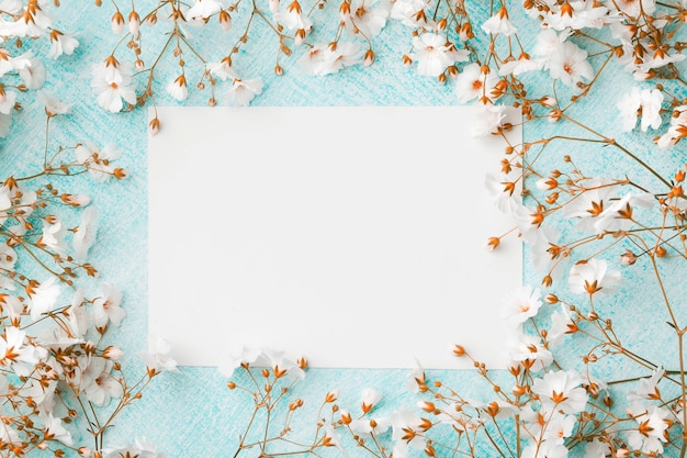 Pusty arkusz papieru otoczony małymi białymi kwiatami.