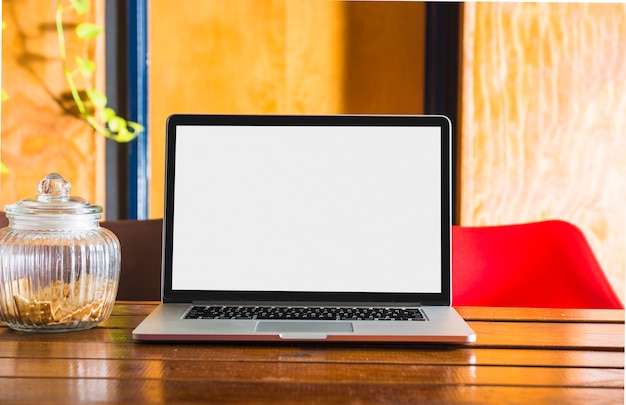 Zdjęcie pusty biały ekran wyświetlania na laptopie nad stołem ze szkła słoik zamknięty