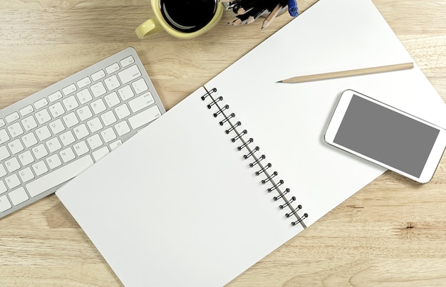 Zdjęcie pusty biały papier i mądrze telefon z czerń ekranem i filiżanką kawy na drewnianym stole