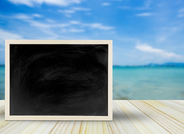 Pusty chalkboard, blackboard na stole z plażowym tłem z kopii przestrzenią