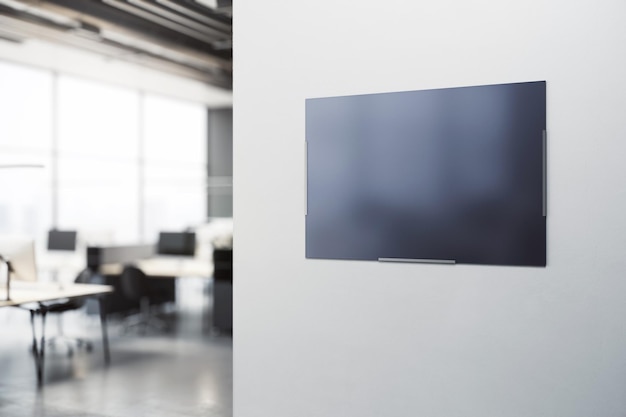 Pusty ciemny ekran telewizora z miejscem na logo lub tekst reklamowy na jasnoszarym tle ściany w nowoczesnym biurze z niewyraźnymi meblami na tle Makieta renderowania 3D