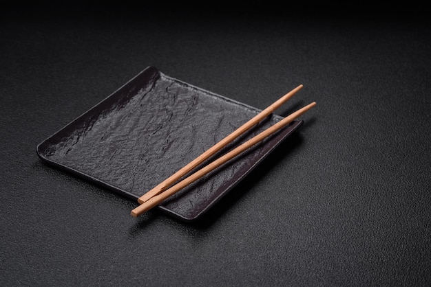 Pusty czarny kwadratowy talerz ceramiczny na ciemnym betonowym tle Gotowanie potraw azjatyckich