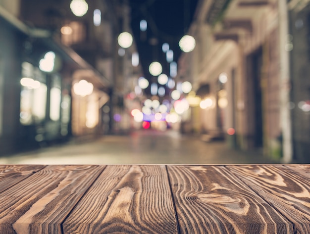 Zdjęcie pusty drewniany stół przed abstrakta zamazanym ulicznym tłem