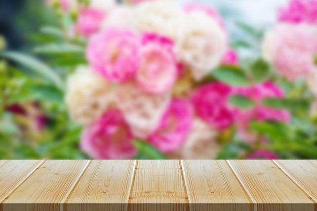 Pusty drewniany stół z niewyraźnym tłem z ogrodu różanego do wyświetlania produktów