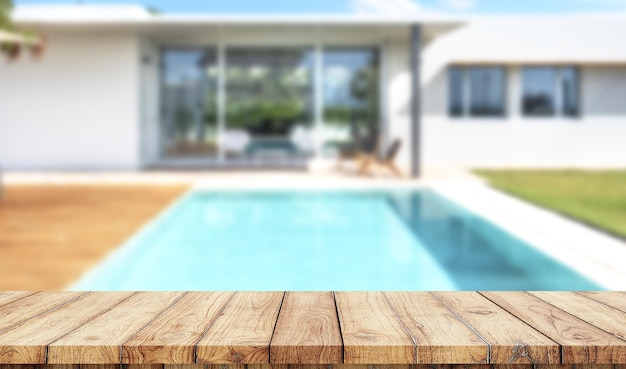 Pusty drewniany stół z zamazanym luksusowym ogrodem z basenem na tle