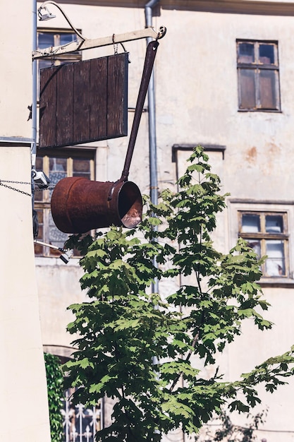 Pusty drewniany znak i duży zardzewiały żelazny Cezve na rogu budynku Miejsce na reklamę