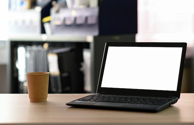Pusty ekran laptopa z kawą na wynos na stole w biurze.