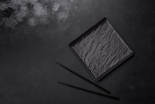 Pusty kwadratowy czarny talerz na ciemnym, nastrojowym tle z miejscem na kopię
