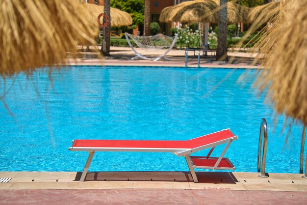 Pusty leżak po stronie basenu w letnim kurorcie. Koncepcja wakacji i ucieczki.