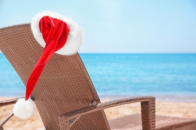 Pusty leżak z santa hat na plaży w pobliżu morza. Koncepcja świąt Bożego Narodzenia