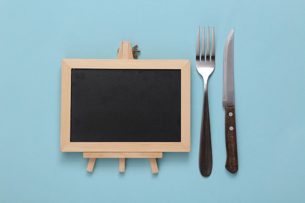 Pusty mini nóż i widelec do tablicy kredowej na niebieskim tle Menu restauracji
