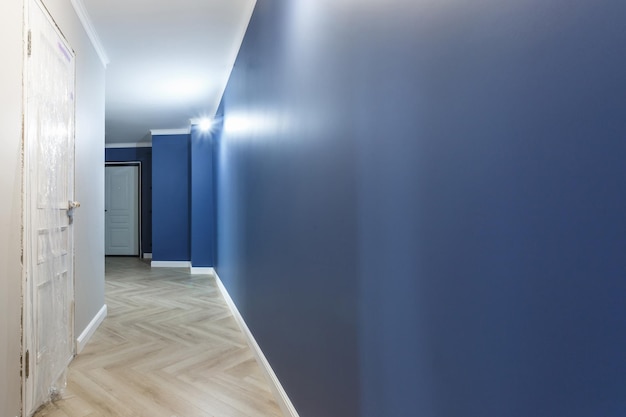 Pusty, nieumeblowany korytarz z minimalnymi naprawami przygotowawczymi z wnętrzem formowania korony białych i niebieskich ścian
