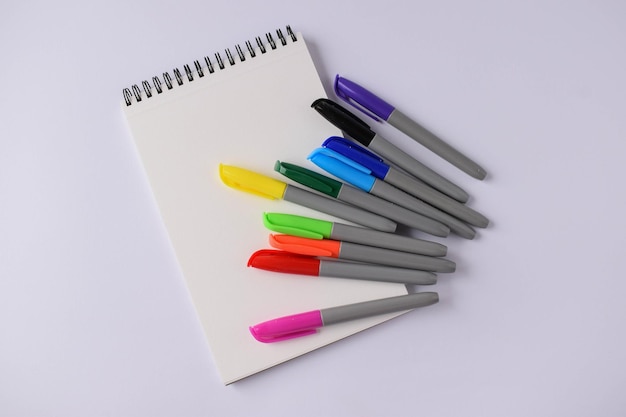 Pusty notatnik i kolorowe pisaki na białym tle Wielokolorowe pisaki dla dzieci