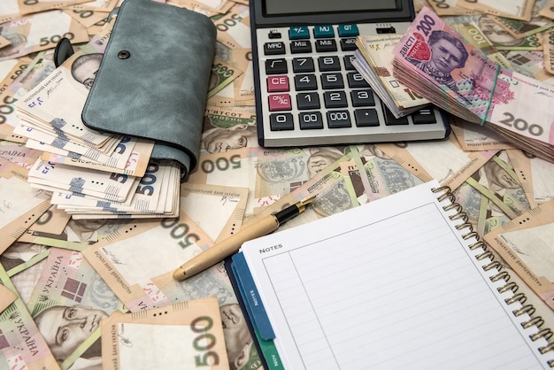 Pusty notatnik, pełny portfel pieniędzy z kalkulatorem na ukraińskich tłach pieniężnych