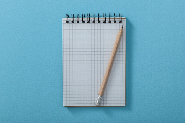 Pusty notatnik z drewnianym ołówkiem na niebieskim tle