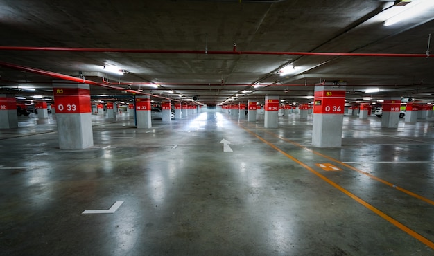 Zdjęcie pusty podziemny parking samochodowy. podziemny parking samochodowy w centrum handlowym lub na międzynarodowym lotnisku. kryty parking. betonowy parking podziemny garaż podłogowy.