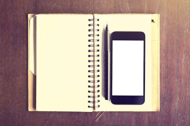 Pusty smartfon z piórem i pamiętnikiem na drewnianym stole makieta